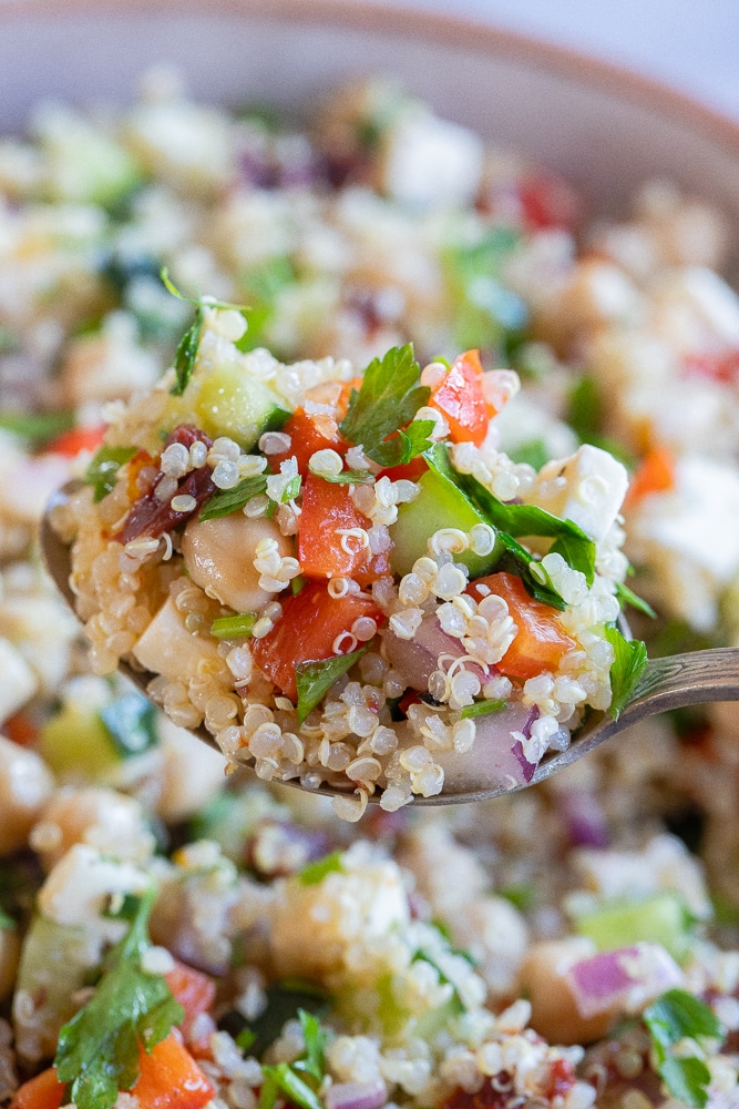 close up of a spoon holding a bite of gluten free quinoa salad with chickpeas