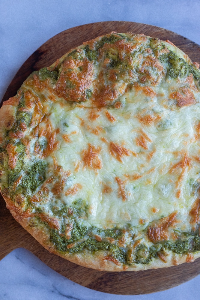 pesto pizza brown and perfect on a cutting board
