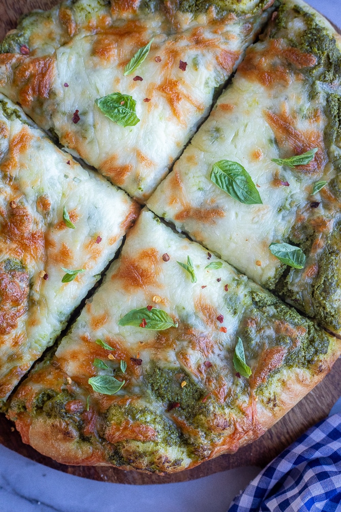 close up of a pesto pizza sliced four ways