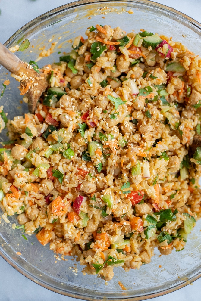 Rice salad mixed together in a serving bowl with vegetables and peanut sauce