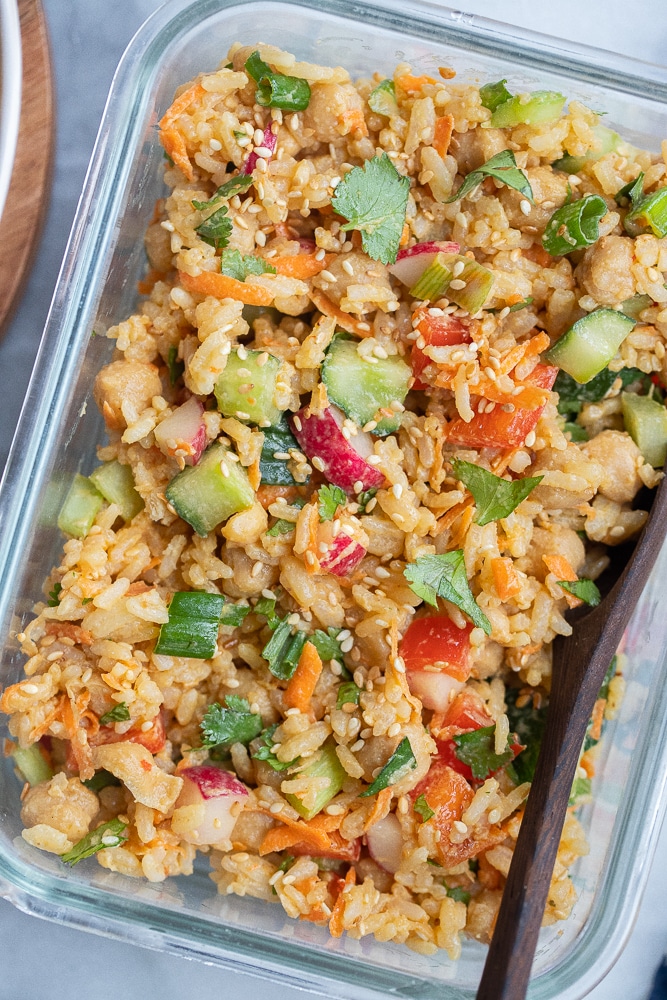 close up of a container of rice and chickpea salad with peanut sauce and veggies