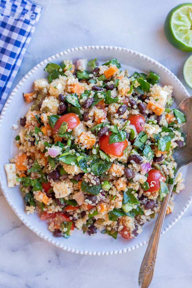 Plate full of vegetarian loaded quinoa salad with a fork and napkin