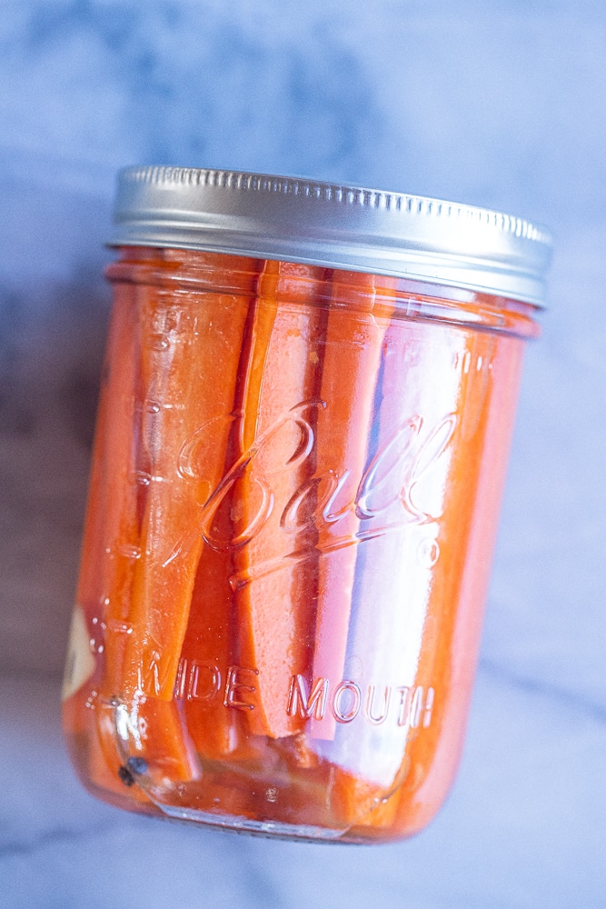 jar of pickled carrots with black peppercorns and garlic