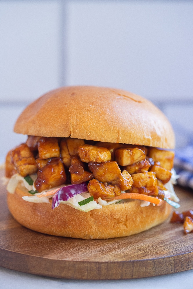 bbq tofu sandwich with coleslaw on a cutting board