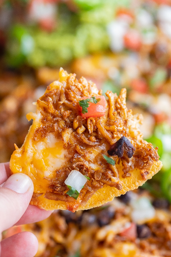 close up of a shredded tofu nacho being held by a hand