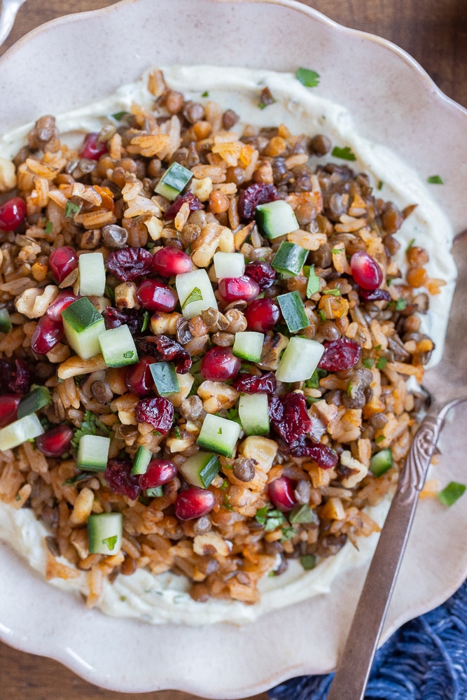 close up of a bowl of lentils and rice topped with cucumber and pomegranate