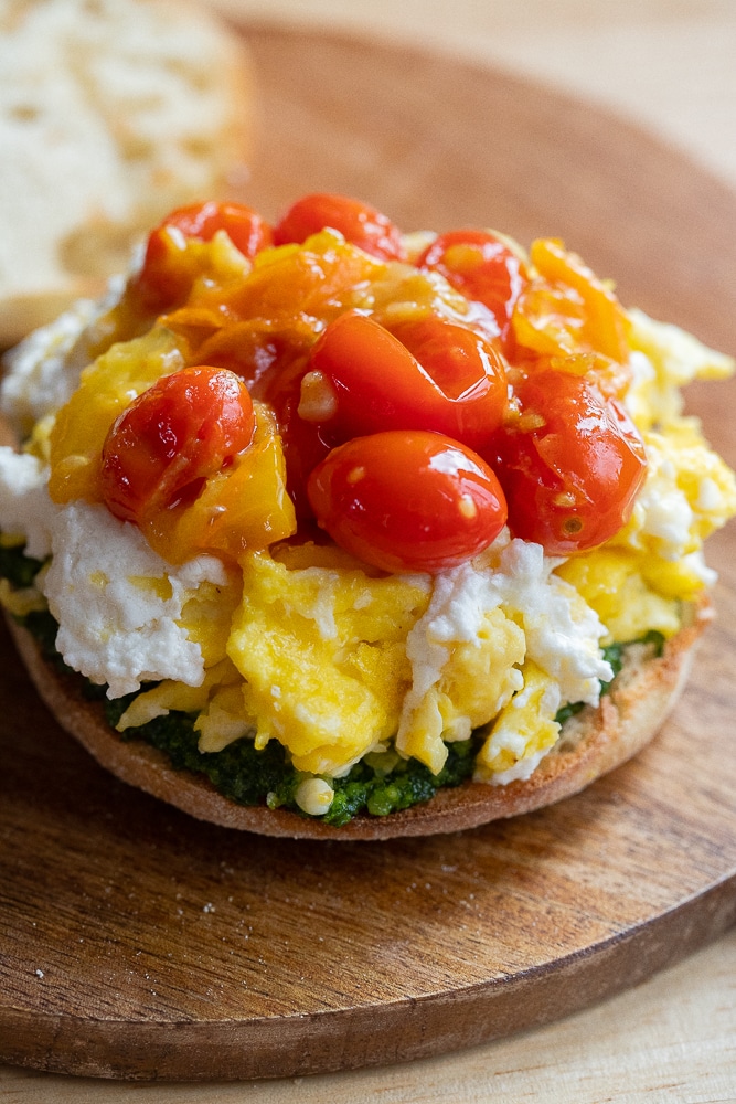 close up of a breakfast sandwich with tomatoes, goat cheese and kale pesto