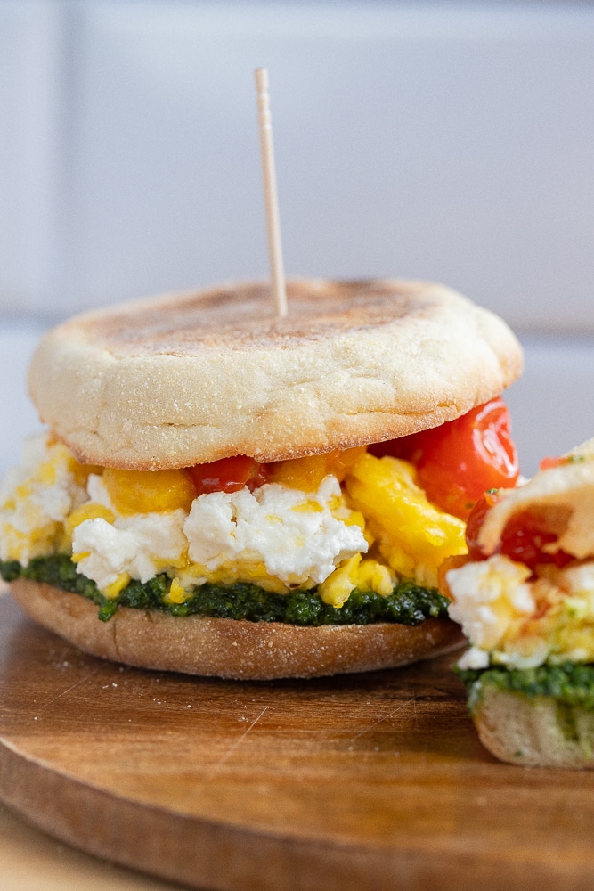 close up of a goat cheese breakfast sandwich with tomatoes and kale pesto