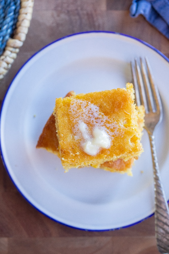 close up of the perfect cornbread recipe on a plate with some butter