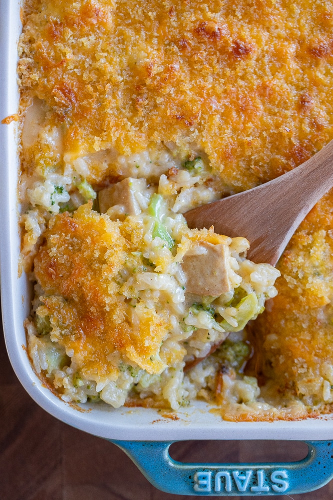 close up of a spoonful of cheesy rice casserole in a oven dish