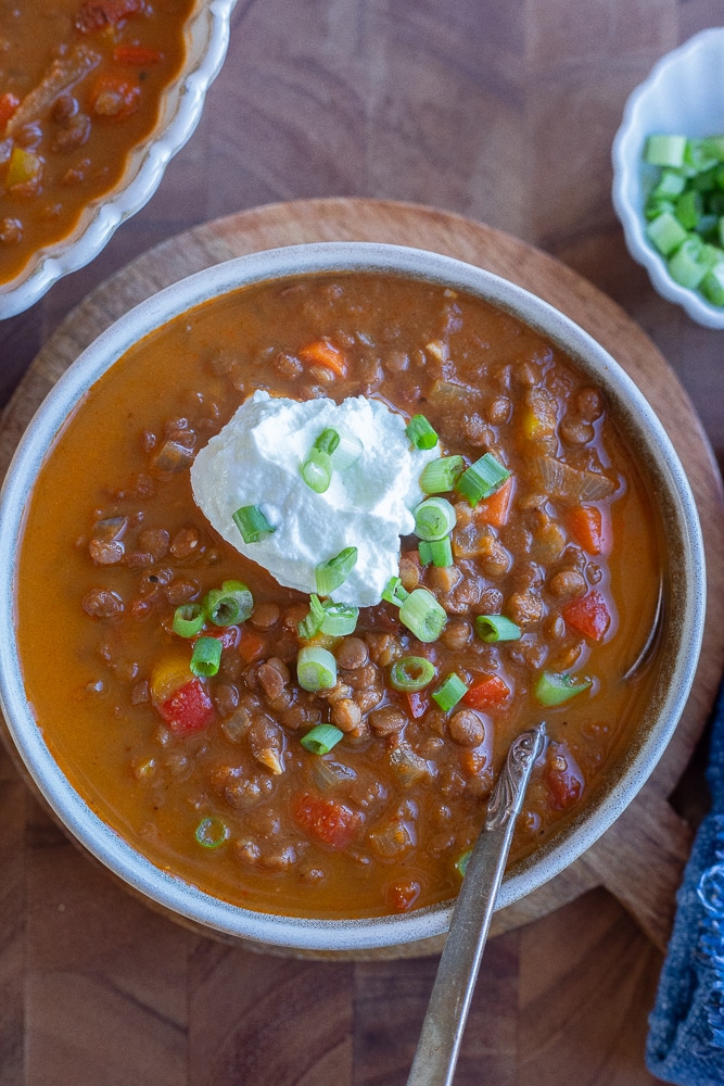 Lentil chili in a bowl topped with greek yogurt and green onion