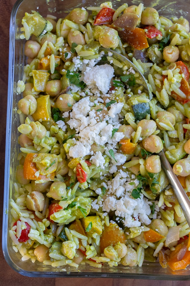 Close up of a chickpea orzo bowl with roasted vegetables and feta cheese and lemon parsley dressing