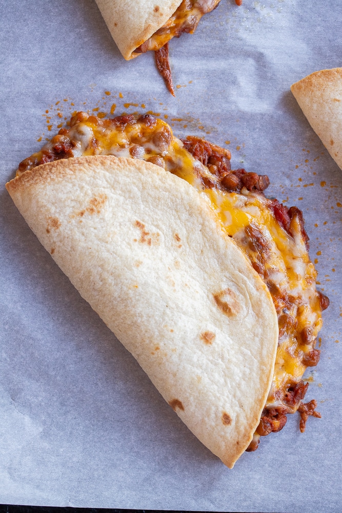 close up of a crispy cheesy lentil taco on a baking sheet