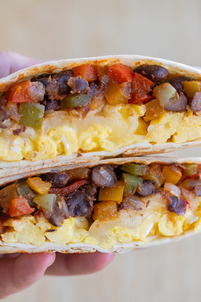 close up of a hand holding a vegetarian black bean fajita egg wrap