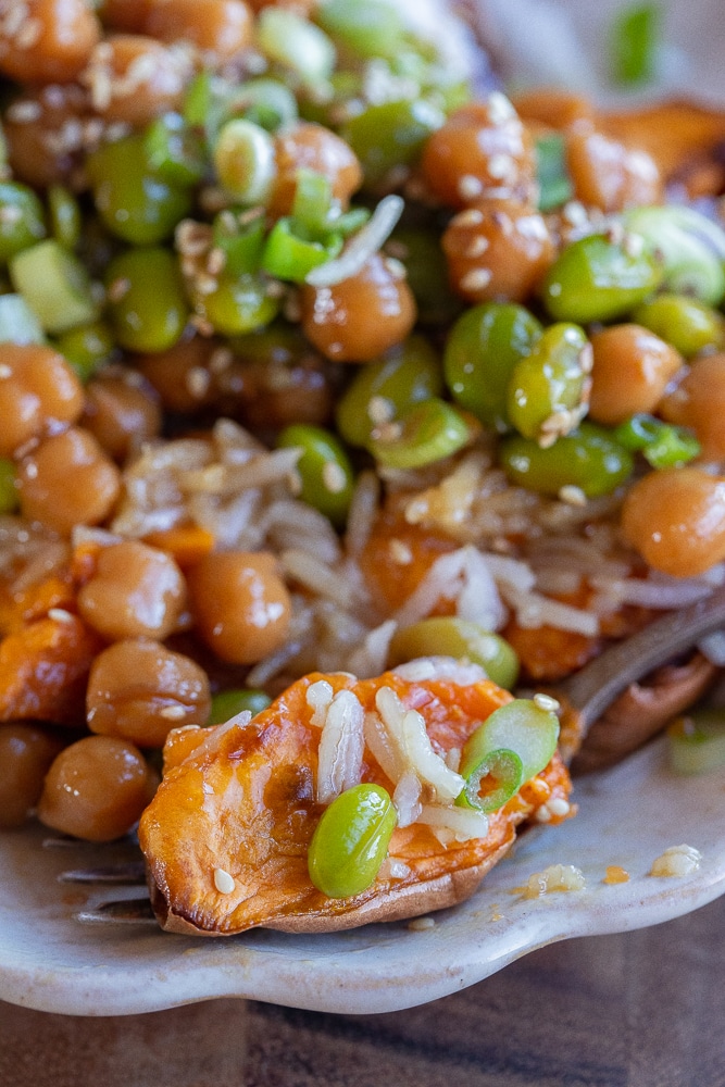 close up of a slice of sweet potato on a fork with edamame and rice