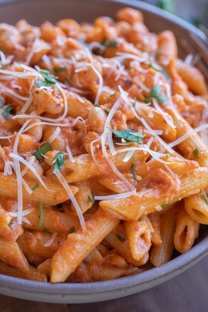 close up of a bowl of creamy red pasta with white beans