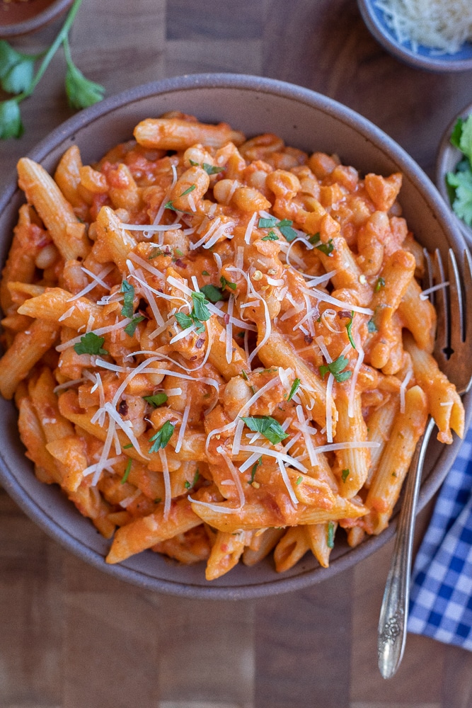 creamy tomato pasta in a dinner bowl topped with parmesan and parsley