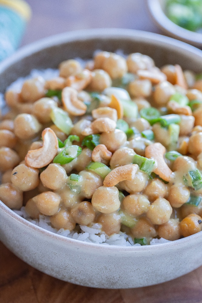 bowl of green curry chickpeas topped with cashews