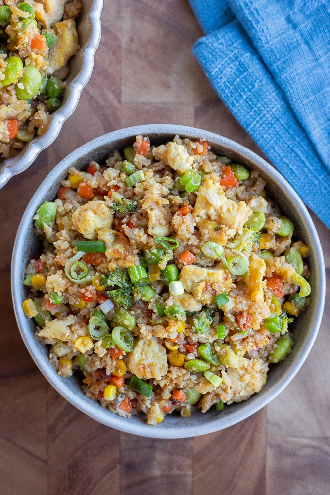 dinner bowl full of loaded vegetarian fried rice topped with green onion