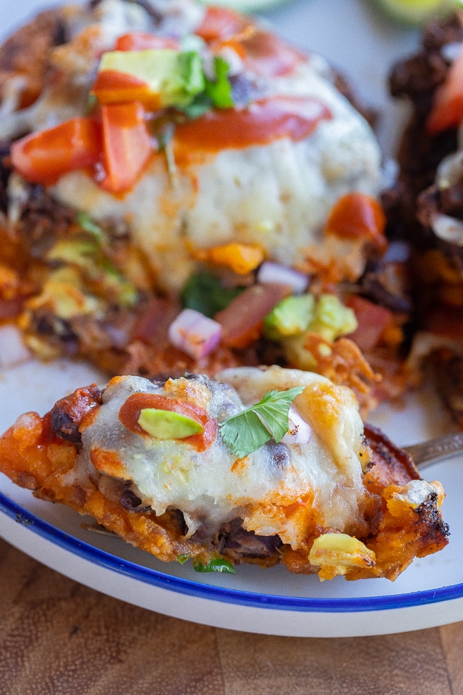 A bite taken out of a black bean cheesy sweet potato