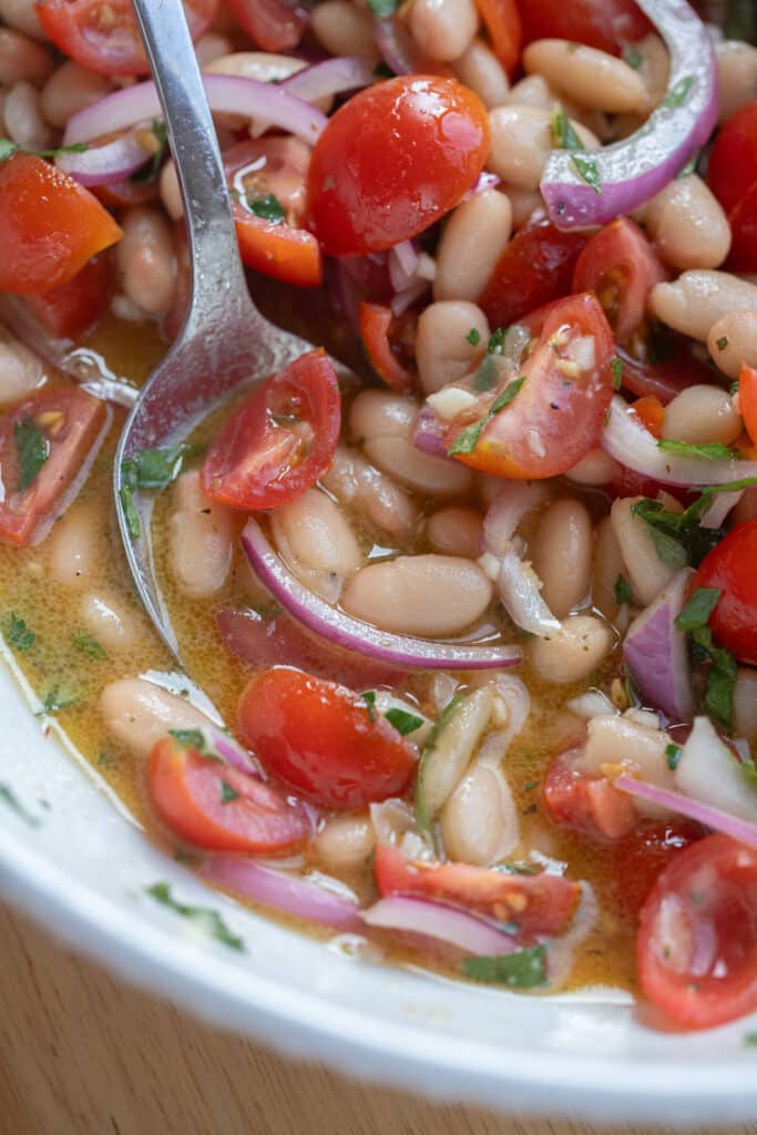 close up of a spoonful of white bean tomato salad with dressing