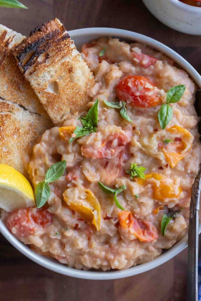 close up of a bowl of refried white beans with cherry tomatoes and toast
