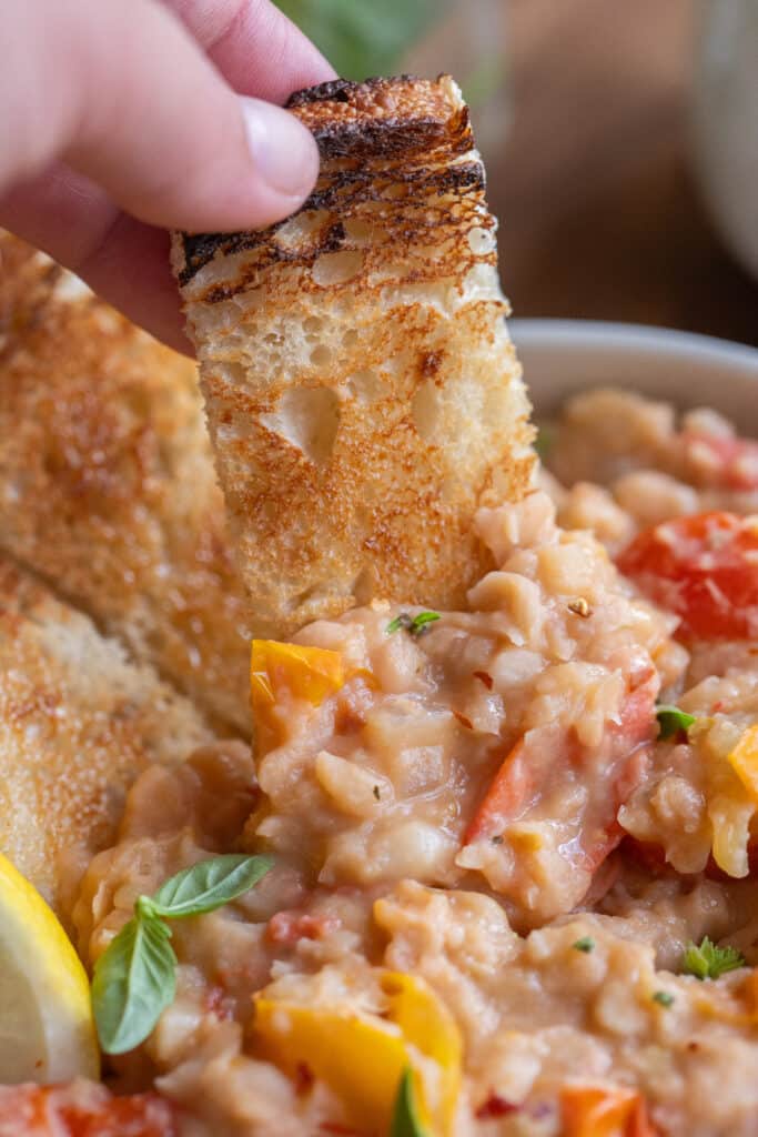 a slice of toast dipped into the smashed white beans
