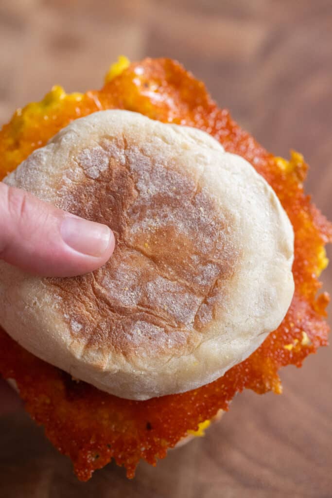 A hand holding a egg and cheese breakfast sandwich