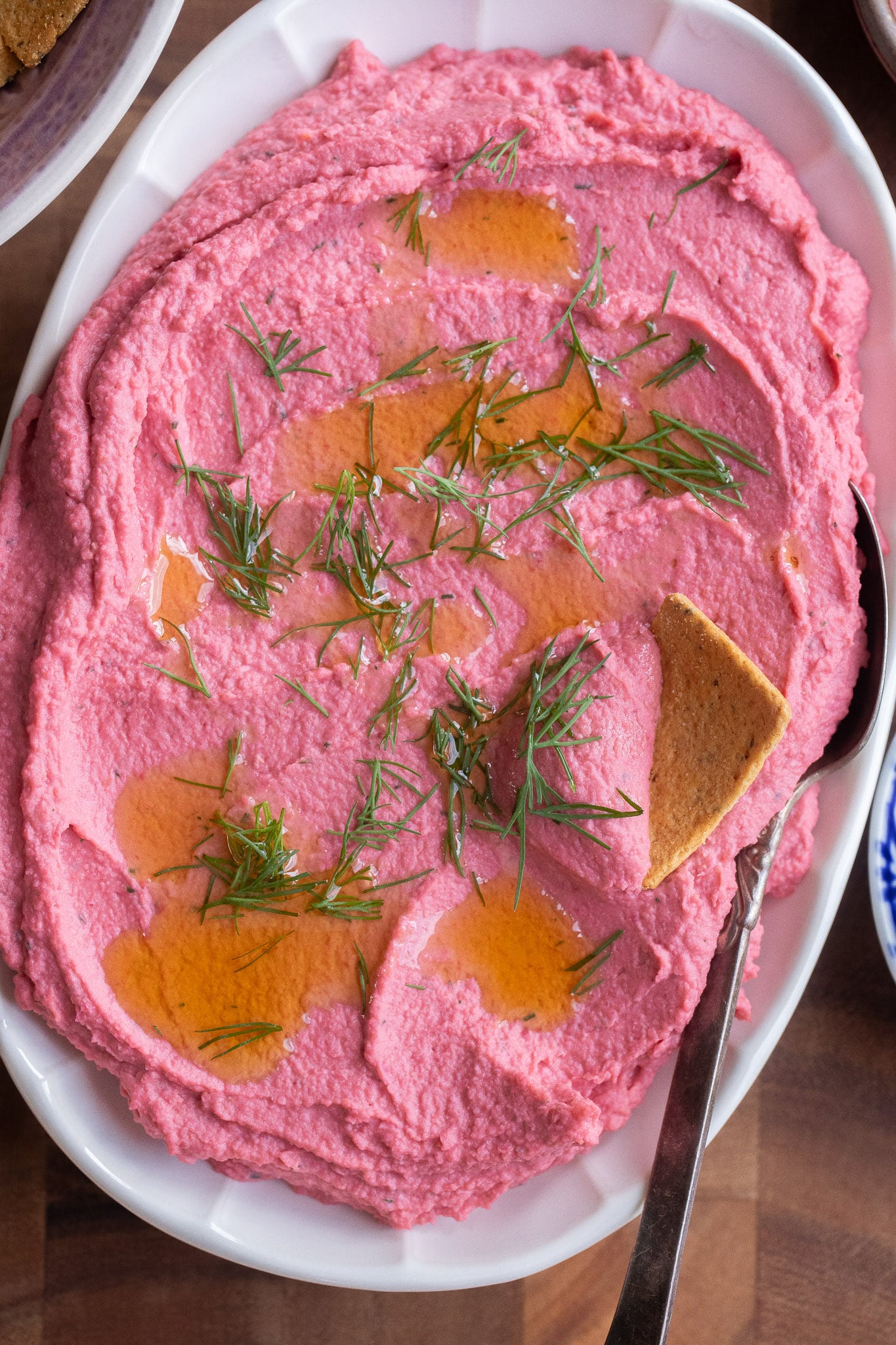 close up of a platter of pickled beetroot hummus topped with olive oil and dill