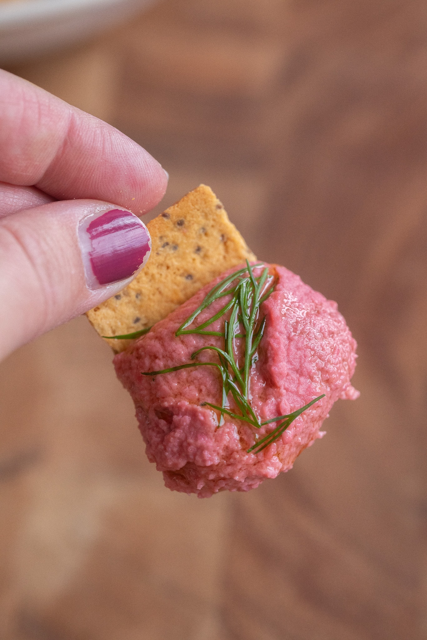 close up of a cracker topped with beet hummus