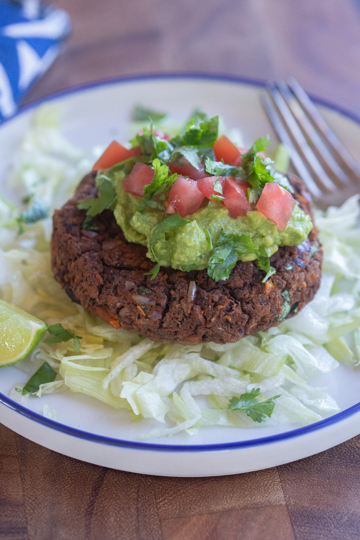 gluten free black bean patty on a plate with lettuce and guacamole